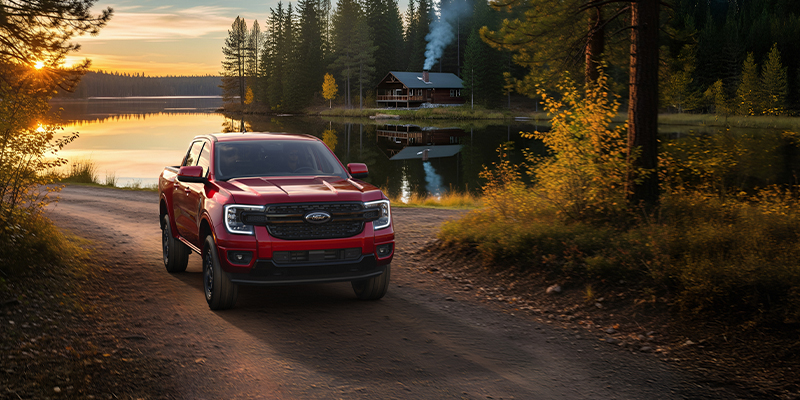 A red Ford Ranger pickup truck parked by a lake.